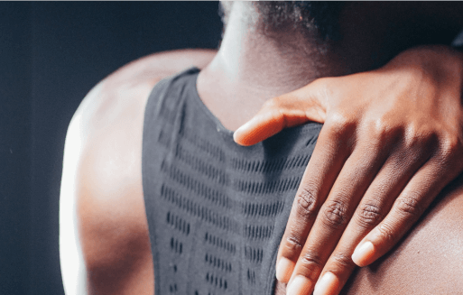 Person reaching over their shoulder to rub their trapezius.